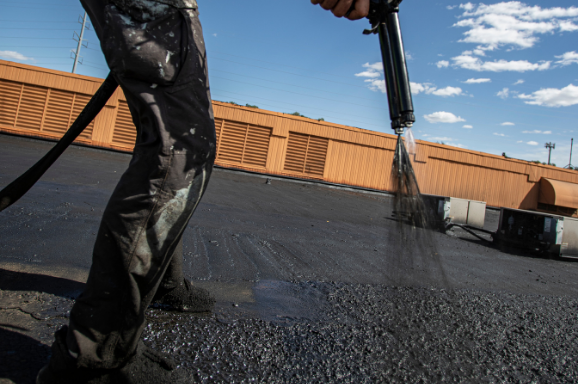 Spraying a black rubber coating on a flat roof